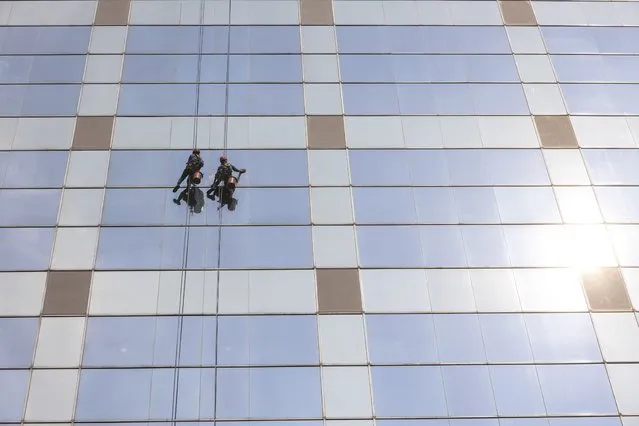 Window cleaners work to clean the glass facade of an office building in Jakarta, Indonesia, 10 August 2023. Indonesia's capital was listed among cities with the worst air quality in the world on 10 August 2023, according to data from IQAir company. Pollutions from crowded traffic and the industrial smoke are believed to contribute most to the poor air quality. (Photo by Mast Irham/EPA)