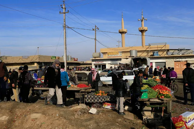 People shop in the street of Gogjali neighborhood in Mosul, Iraq, December 4, 2016. (Photo by Thaier Al-Sudani/Reuters)