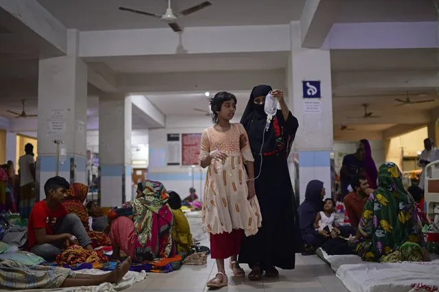 A child suffering from dengue is helped by a family member as she walks inside the dengue ward of Mugda Medical College and Hospital in Dhaka, Bangladesh, Thursday, August 10, 2023. (Photo by Mahmud Hossain Opu/AP Photo)
