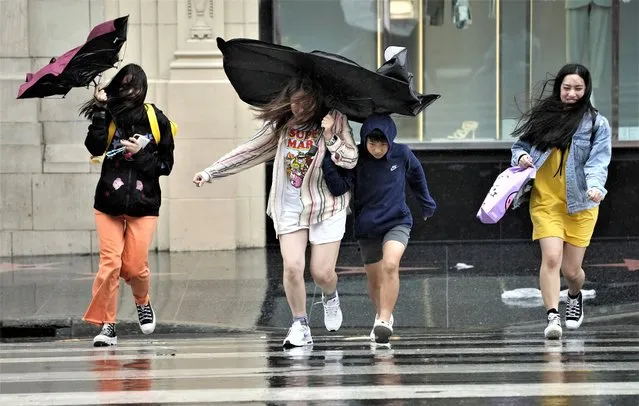 Pedestrians fight wind and rain as they cross Hollywood Boulevard during Tropical Storm Hilary, Sunday, August 20, 2023, in Los Angeles. (Photo by Chris Pizzello/AP Photo)