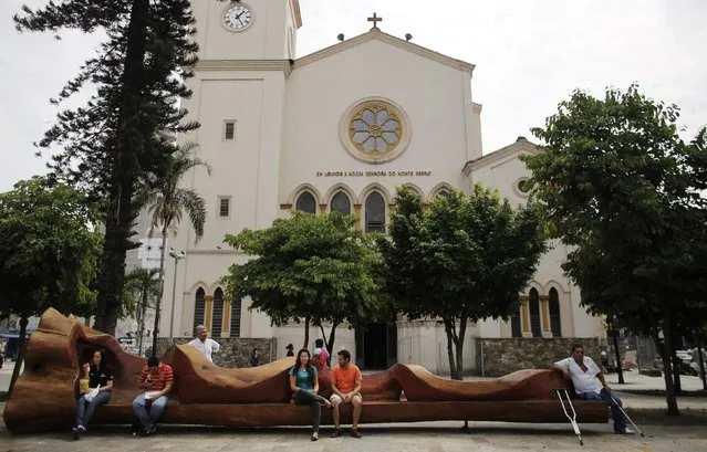 Residents sit on a bench made from a tree, which is created by Brazilian artist Hugo Franca (not pictured) at Largo da Batata square in Sao Paulo March 17, 2015. (Photo by Nacho Doce/Reuters)