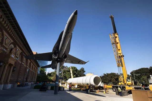 One of two rocket motors are temporarily placed next to an F-18 fighter jet on the grounds of the California Science Center in Los Angeles on Wednesday October 11, 2023. The two giant rocket motors required to display with the retired NASA space shuttle Endeavour as if it's about to blast off have arrived at the Los Angeles museum, completing their long journey from the Mojave Desert. The 116-foot-long motors, which look like giant white cylinders, were trucked over two days from the Mojave Air and Space Port to LA's Exposition Park, where the California Science Center's Samuel Oschin Air and Space Center is being built to display Endeavour. (Photo by Richard Vogel/AP Photo)