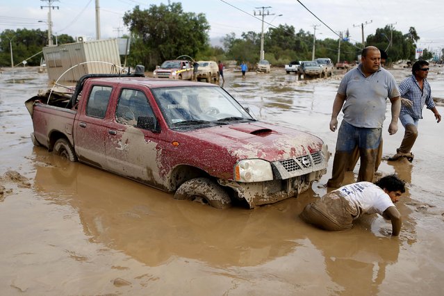 Locals prepare to tow a car away from the mud at Copiapo city, March 26, 2015. (Photo by Ivan Alvarado/Reuters)