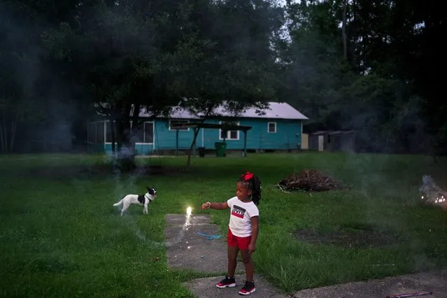 Ayannie Morris, 5, plays with a sparkler as her dog Oreo and mom Ashleigh Schneider (not pictured) sits nearby at their home in Mandeville, Louisiana, U.S., July 4, 2021. (Photo by Kathleen Flynn/Reuters)