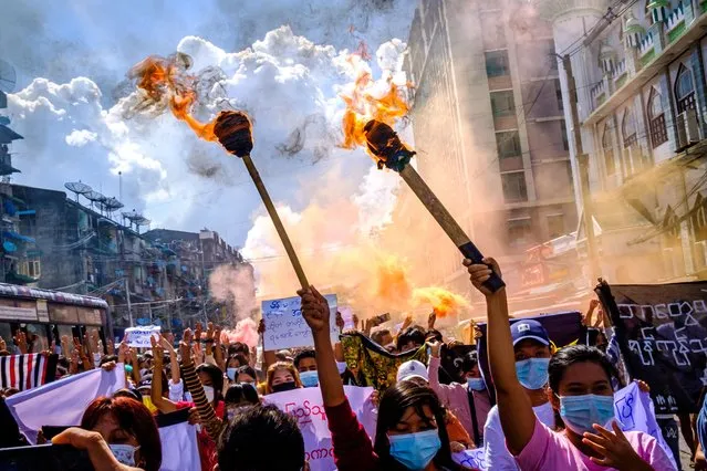 Women carry burning torches as they march during a demonstration against the military coup in Yangon, Myanmar on July 14, 2021. (Photo by AFP Photo/Stringer)