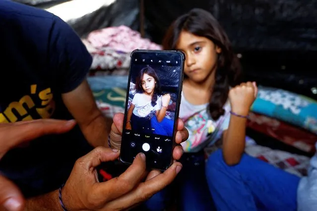 Daughter of Palestinian man Ali Daba, who decided with his wife to split their children up and mark them with bracelets to help identify them, in fear of them being killed in Israeli strikes, shows her bracelet at their shelter in Khan Younis in the southern Gaza Strip on October 24, 2023. (Photo by Ibraheem Abu Mustafa/Reuters)