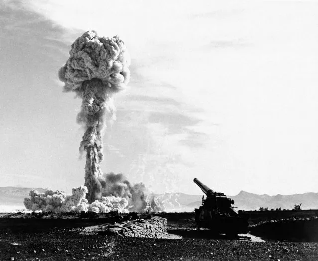 The towering lacy mushroom from the atomic cannon's first test rises from desert floor at Frenchman's flat, near Las Vegas, Nevada on May 25, 1953. The 280-mm gun which tossed the shell to its destination six or seven mile away is in the foreground. The rifle was touched off electrically, with the gun-loading crew entrenched a safe distance away. This picture, released on May 27, by the air force, was made probably about 10 seconds after the explosion. (Photo by AP Photo)
