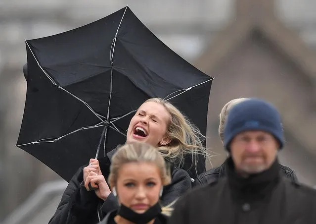 A woman reacts as she shields herself from rain during strong winds, London, United Kingdom on May 21, 2021. (Photo by Toby Melville/Reuters)