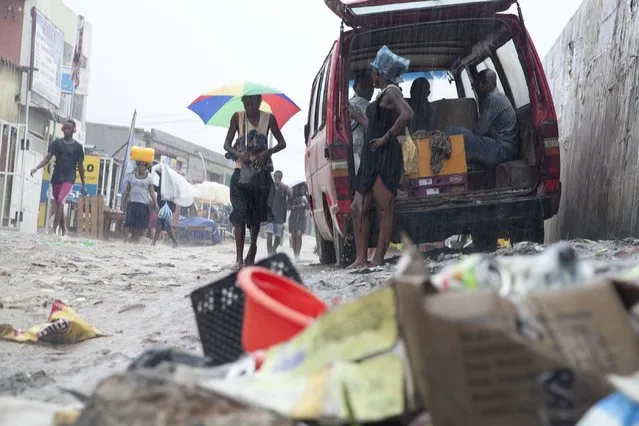 People walk past a pile of garbage along a street during rainfall, in Luanda,  Angola, in this picture taken February 10, 2016. When a plunge in oil prices prompted Angola's government to slash public spending last year, street trader Antonio Simao Baptista had no idea it would leave his rundown suburb overwhelmed by filth and disease. The budget of Africa's second largest oil exporter has been cut again this year and is 40 percent lower than two years ago. (Photo by Herculano Corarado/Reuters)
