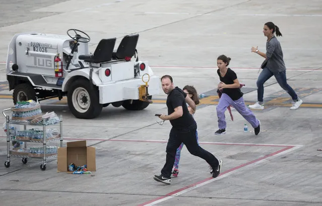 People run on the tarmac at Fort Lauderdale Hollywood International Airport, Friday, January 6, 2017, in Fort Lauderdale, Fla., after a shooter opened fire inside a terminal of the airport, killing several people and wounding others before being taken into custody. (Photo by Wilfredo Lee/AP Photo)