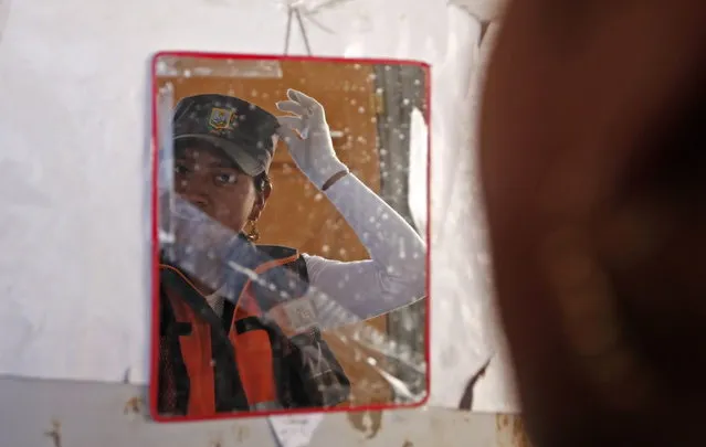 In this November 28, 2013 photo, the image of an Aymara woman adjusting her khaki green police-style cap is reflected in a mirror in El Alto, Bolivia. (Photo by Juan Karita/AP Photo)