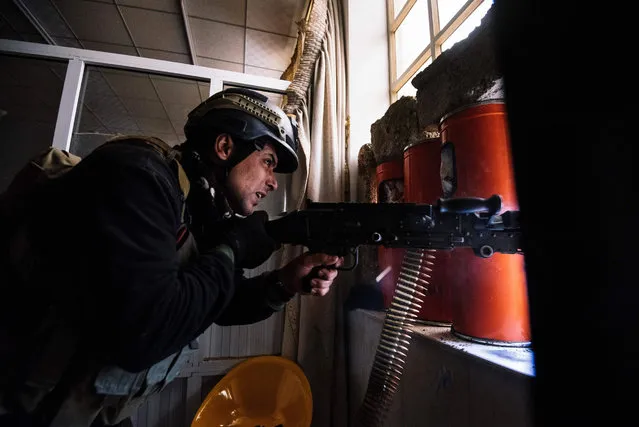 A member of the Iraqi special forces' Counter-Terrorism Service (CTS) fires his machine gun as he holds a position inside Mosul's university on January 15, 2017, during an ongoing military operation against Islamic State (IS) group jihadists. (Photo by Dimitar Dilkoff/AFP Photo)
