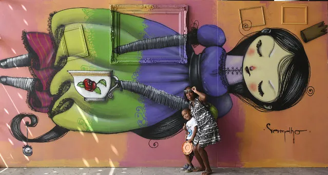 Visitors pose for a picture in front of graffiti art created by Brazilian artist Vermelho during the 3rd annual Graffiti Fine Art Biennial International exhibit, at the Pavilion of Brazilian Cultures, in Sao Paulo, Brazil, Tuesday, April 21, 2015. The month-long event features the work of more than 60 street artists, representing 11 countries. (Photo by Andre Penner/AP Photo)
