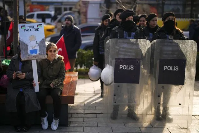 A young girl holds a placard next to Turkish police officers during a protest in support of Palestinians and calling for an immediate ceasefire in Gaza, in Istanbul, Turkey, Sunday, January 14, 2024. (Photo by Emrah Gurel/AP Photo)