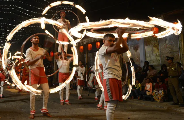 Sri Lankan fire dancers perform in a procession in front of the Gangarama Temple during the Navam Perahera festival in Colombo on February 9, 2017. Monks, drummers, dancers and some 50 trained elephants, mostly from central part of the island, thronged into Colombo from various regions of Sri Lanka to participate in the city's biggest two day annual Buddhist procession starting February 9. (Photo by Lakruwan Wanniarachchi/AFP Photo)