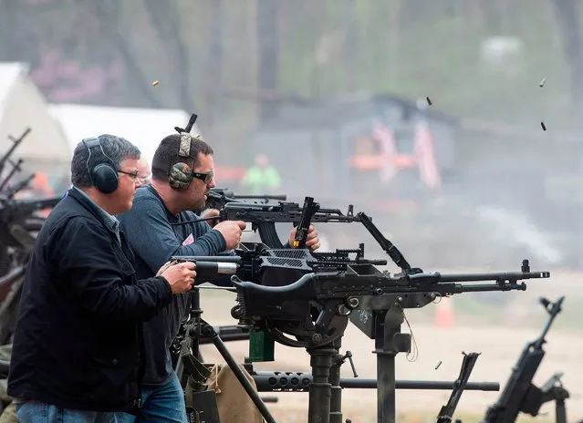 People fire machine guns on the main firing line during the Knob Creek Machine Gun Shoot and Military Gun show in Bullitt County near West Point, Kentucky on April 13, 2019. The Machine Gun Shoot and Military Gun show attracts thousands of visitors from across the country and around the world for the two day event featuring machine gun owners firing millions of rounds. Machine gun owners can reserve spots on the main firing line, but the waiting list is up to 10 years. On a secondary firing line other vendors rent out machine guns to anyone willing to pay for a few rounds. Started in 1965 by Biff Sumner and friends having a cookout and shooting machine guns, it grew into the biggest machine gun shoot in the world. (Photo by Andrew Caballero-Reynolds/AFP Photo)