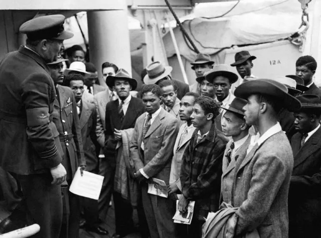 People arriving from the  Caribbean are welcomed by RAF officials from the Colonial Office after the ex-troopship HMT Empire Windrush docks, at Tilbury, England, June 22, 1948.  Seventy-five years ago, a ship landed at Tilbury Dock near London, carrying more than 800 passengers from the Caribbean to new lives in Britain. The arrival of the Empire Windrush in 1948 has become a symbol of the post-war migration that transformed the U.K. and its culture. (Photo by PA Wire via AP Photo)