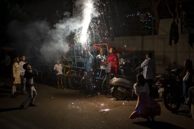 People watch a firecracker light up during Diwali celebrations in New Delhi, India, Thursday, November 4, 2021. Millions of people across Asia are celebrating the Hindu festival of Diwali, which symbolizes new beginnings and the triumph of good over evil and light over darkness. (Photo by Altaf Qadri/AP Photo)
