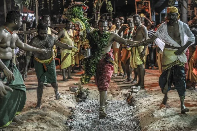 This photo taken on May 3, 2015 shows a Malaysian Hindu devotee (C) carrying an idol walking on hot coals during a firewalking festival at a temple in Kuala Lumpur. Firewalking or “Thimithi” is a festival originating in southern India that is celebrated in honour of Draupadi, who is considered the incarnation of Mariamman. (Photo by Mohn Rasfan/AFP Photo)