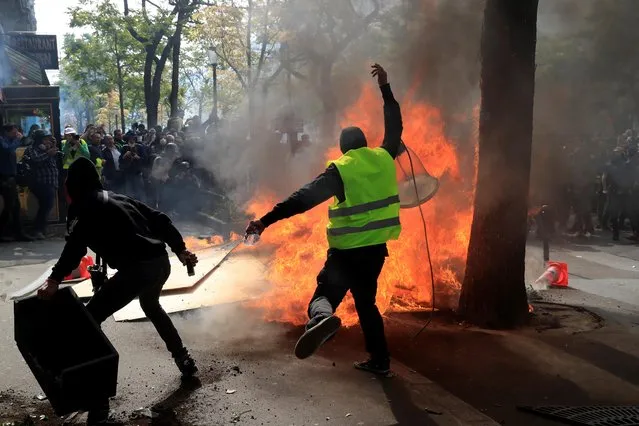 Masked protesters burn street furniture during clashes with riot police as part of the traditional May Day labor union march with French unions and yellow vests protesters in Paris on May 1, 2019. (Photo by Gonzalo Fuentes/Reuters)