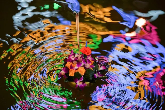 A krathongs (floating baskets) floats on a canal during the Loy Krathong festival, which is held as a symbolic apology to the goddess of the river in Bangkok, Thailand, November 19, 2021. (Photo by Chalinee Thirasupa/Reuters)