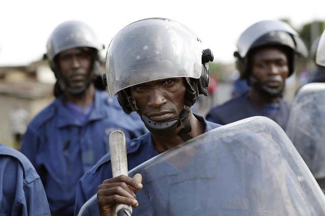 Police keeps watch as protesters march through the Musaga district of Bujumbura, in Burundi, Monday, May 11, 2015. Police and army negotiated with over 2000 protesters to allow delivery trucks to enter the city. (Photo by Jerome Delay/AP Photo)