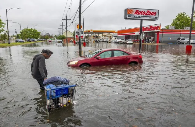 People carry their belongings down a flooded Broad Street in New Orleans, during a severe rainstorm on Wednesday, April 10, 2024. (Photo by Chris Granger/The Times-Picayune/The New Orleans Advocate via AP Photo)
