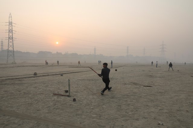 A boy plays cricket on the floodplains of the Yamuna river on a smoggy morning in New Delhi, India, November 17, 2021. (Photo by Anushree Fadnavis/Reuters)