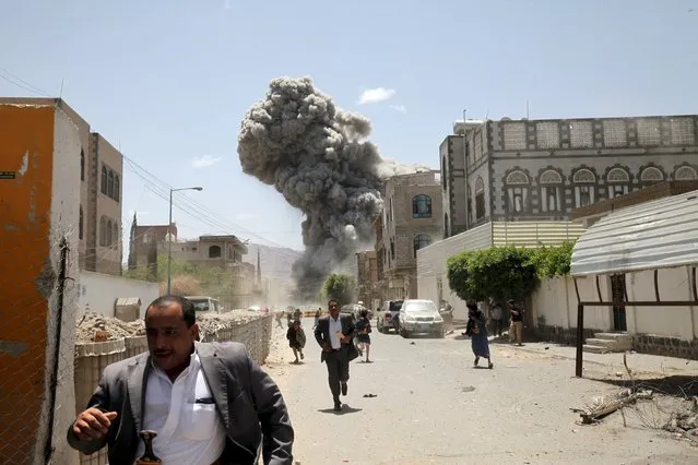 People flee as smoke billows after air strikes hit the house of Yemen's former President Ali Abdullah Saleh in Sanaa May 10, 2015. (Photo by Mohamed al-Sayaghi/Reuters)