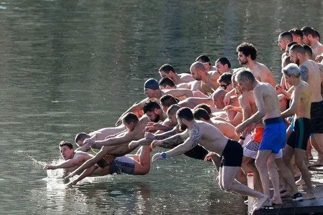 Bulgarian Orthodox faithfuls dive into water of a lake to catch a wooden crucifix as part of Epiphany Day celebrations in Sofia, on January 6, 2022. As a tradition, an Eastern Orthodox priest throws a cross in the river and it is believed that the one who retreives it will be healthy throughout the year as well as all those who dance in the icy waters. (Photo by Nikolay Doychinov/AFP Photo)