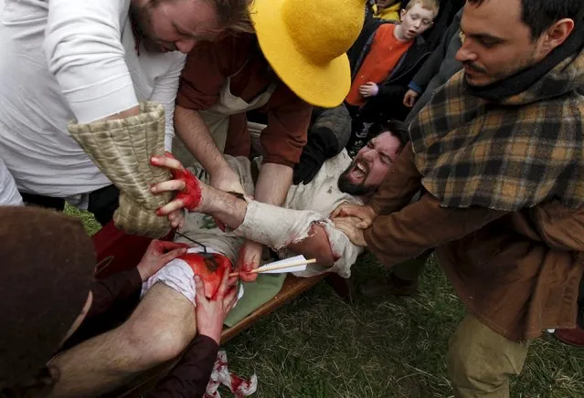 Participants in medieval costumes perform the treatment of a mock arrow wound during an annual re-enactment of a battle near the village of Libusin, Czech Republic, April 23, 2016. (Photo by David W. Cerny/Reuters)