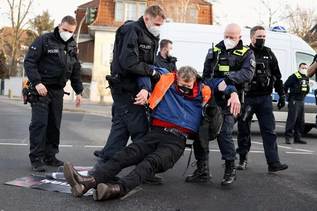 Police officers remove a “Letzte Generation” (Last Generation) activist who protests against food waste and in support of an agricultural change to reduce greenhouse gas emissions, in Berlin, Germany, February 14, 2022. (Photo by Christian Mang/Reuters)
