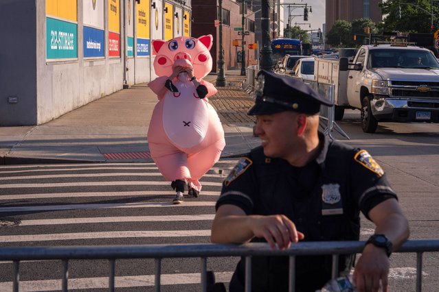 A protestor wearing a pig costume walks behind an NYPD officer outside of the New York City Police Foundation Gala held at The Intrepid Museum on June 6, 2024 in New York City. Protestors were calling for the release of donors names, stopping the funding of 'Police terror' and to demilitarise the subway. (Photo by Adam Gray/Getty Images)