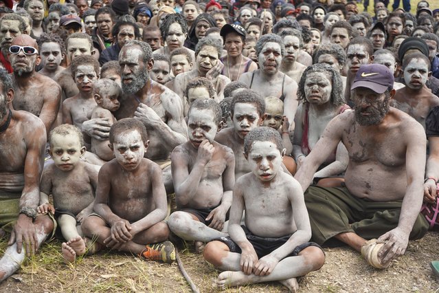 A group of survivors from the May 24 landslide in Inga Province, are smeared in mud as a sign of mourning, gather at an event where Prime Minister James Marape was to address them at Kaokalom village, in the highlands of Papua New Guinea, Friday May 31, 2024. Marape visited the site of a major landslide, which is estimated to have buried hundreds of villagers in the South Pacific island nation's mountainous interior over a week ago and left the ground too unstable for heavy earthmoving machines to help clear up the mess. (Photo by Noreen Chambers, UNICEF PNG via AP Photo)