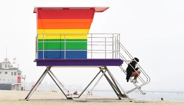 A woman sits on the steps to the new rainbow-colored Pride lifeguard tower on June 16, 2021 in Long Beach, California. The new lifeguard tower was unveiled on June 15, in time for LGBTQ Pride Month, after being burned down by vandals in March. (Photo by Frederic J. Brown/AFP Photo)