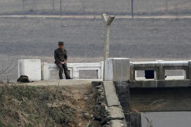 A North Korean soldier sits on the banks of the Yalu River in Sinuiju, North Korea, which borders Dandong in China's Liaoning province, April 16, 2017. (Photo by Aly Song/Reuters)