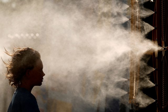 Ten-year-old Michael Mullenax, from Lees Summit, Mo., cools off in a mister at Kauffman Stadium before a baseball game between the Kansas City Royals and the Miami Marlins, Monday, June 24, 2024, in Kansas City, Mo. Temperatures in the Kansas City metro topped 100 degrees for the first time this summer. (Photo by Charlie Riedel/AP Photo)