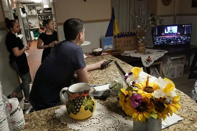 Dmytro Kovalenko, foreground, manager of Ukrainian restaurant Streecha in New York, and two employees, watch Ukrainian President Volodymyr Zelenskyy deliver a virtual address to the U.S. Congress, Wednesday, March 16, 2022. (Photo by Richard Drew/AP Photo)