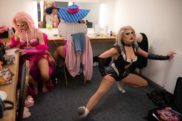 Drag queens Josh Hanson (L), playing “Candy Caned”, Craig Colley (R), playing Bille Eyelash, and Lew Ray (C), playing “ZeZe Van Cartier” warmup as they prepare to leave their dressing room before a performance of “Queenz – The Show With Balls” at the Blackpool Grand Theatre as part of the show's UK tour, in Blackpool, northern England on March 28, 2023. The two-hour Queenz show features 5 drag queens performing a set list of remixed and reimagined pop anthems. The drag queens spend up to five hours perfecting their hair, make-up and outfit before each show. (Photo by Oli Scarff/AFP Photo)