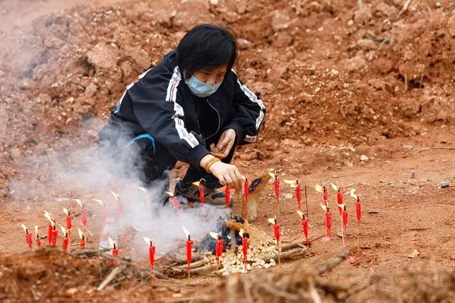 A woman surnamed Liang, 60, takes part in a Buddhist ceremony in honor of the victims in a field close to the entrance of Simen village, near the site where a China Eastern Airlines Boeing 737-800 plane flying from Kunming to Guangzhou crashed, in Wuzhou, Guangxi Zhuang Autonomous Region, China on March 22, 2022. (Photo by Carlos Garcia Rawlins/Reuters)