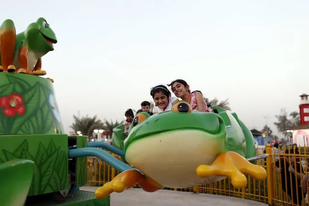Iraqi children take a ride at an amusement park as they celebrate the Muslim festival of Eid al-Fitr celebrations, marking the end of the Muslim fasting month of Ramadan in Baghdad, July 17, 2015. (Photo by Thaier al-Sudani/Reuters)