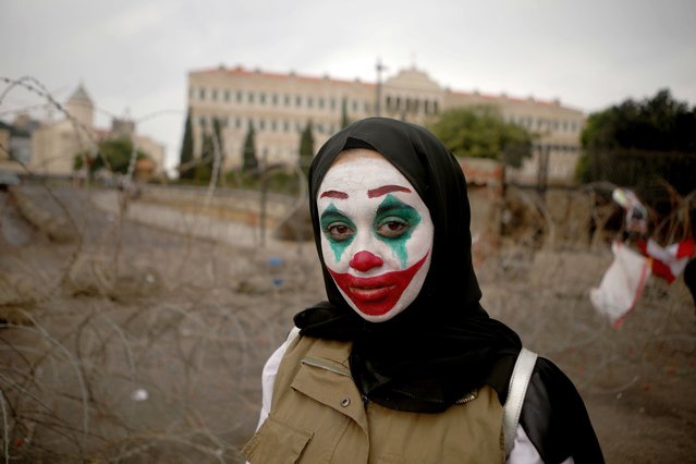 A Lebanese woman with her face painted with the character of the Joker takes part in a protest in downtown Beirut on October 23, 2019 as demonstrations to demand better living conditions and the ouster of a cast of politicians who have monopolised power and influence for decades continue. (Photo by Patrick Baz/AFP Photo)