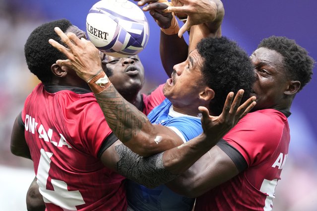 Samoa's Vaa Apelu Maliko retains the ball despite the efforts of Kenya's Vincent Onyala, left and Kenya's Nygel Pettersan Amaitsa, during the men's Rugby Sevens Pool B match between Samoa and Kenya, at the 2024 Summer Olympics, in the Stade de France, Thursday, July 25, 2024, in Saint-Denis, France. (Photo by Tsvangirayi Mukwazhi/AP Photo)