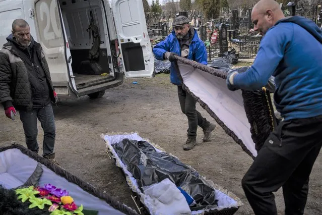 Cemetery workers prepare the coffin for a person killed during the war with Russia, in Bucha, in the outskirts of Kyiv, Ukraine, Monday, April 11, 2022. (Photo by Rodrigo Abd/AP Photo)