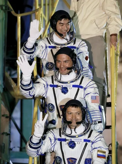 The International Space Station (ISS) crew members Kjell Lindgren of the U.S. (C), Oleg Kononenko of Russia (bottom) and Kimiya Yui of Japan wave as they board the Soyuz TMA-17M spacecraft at the Baikonur cosmodrome, Kazakhstan, July 23, 2015. (Photo by Yuri Kochetkov/Reuters)