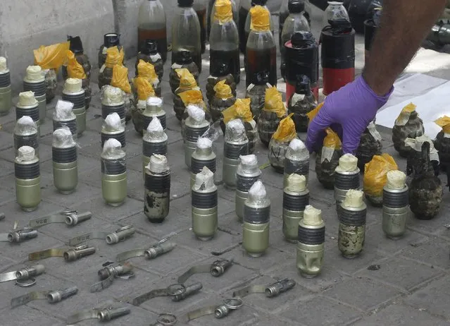 A member of the Bomb Disposal Squad places hand grenades in a line after defusing them along a sidewalk outside Jinnah International Airport in Karachi, June 9, 2014. REUTERS/Athar Hussain