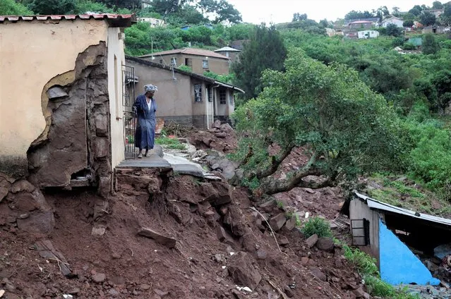 A woman stands at her front door after heavy rains caused flood damage in KwaNdengezi, Durban, South Africa, April 12, 2022. (Photo by Rogan Ward/Reuters)