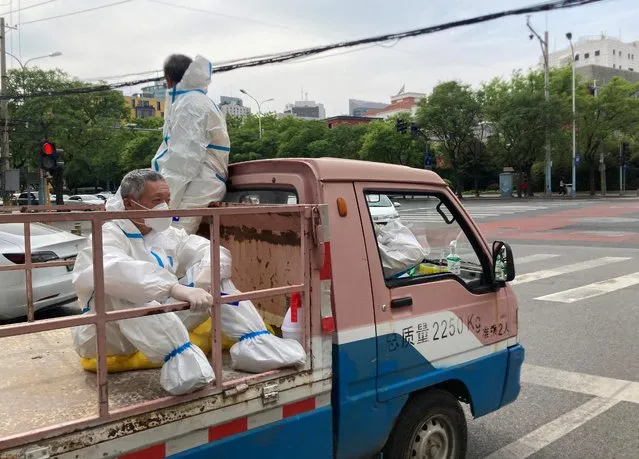 Workers in protective suits sit at the back of a truck on a street, amid the coronavirus disease (COVID-19) outbreak, in Chaoyang district of Beijing, China on May 11, 2022. (Photo by Martin Pollard/Reuters)