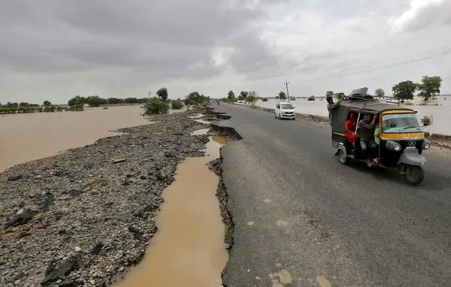 Vehicles move through the damaged national highway after heavy rains on the outskirts of Ahmedabad, India, July 31, 2015. (Photo by Amit Dave/Reuters)