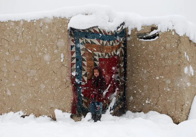 An internally displaced Afghan girl stands at the door of her shelter during a snowfall in Kabul, Afghanistan on January 6, 2020. (Photo by Mohammad Ismail/Reuters)